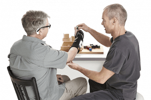 Therapist works with patient wearing ReGrasp for hand therapy