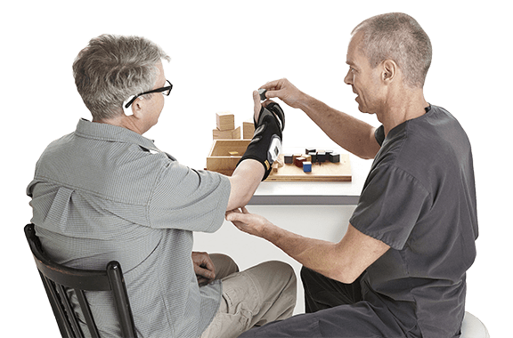 Therapist works with patient wearing ReGrasp for hand therapy